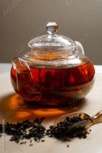 Black tea brewed in teapot on wooden table
