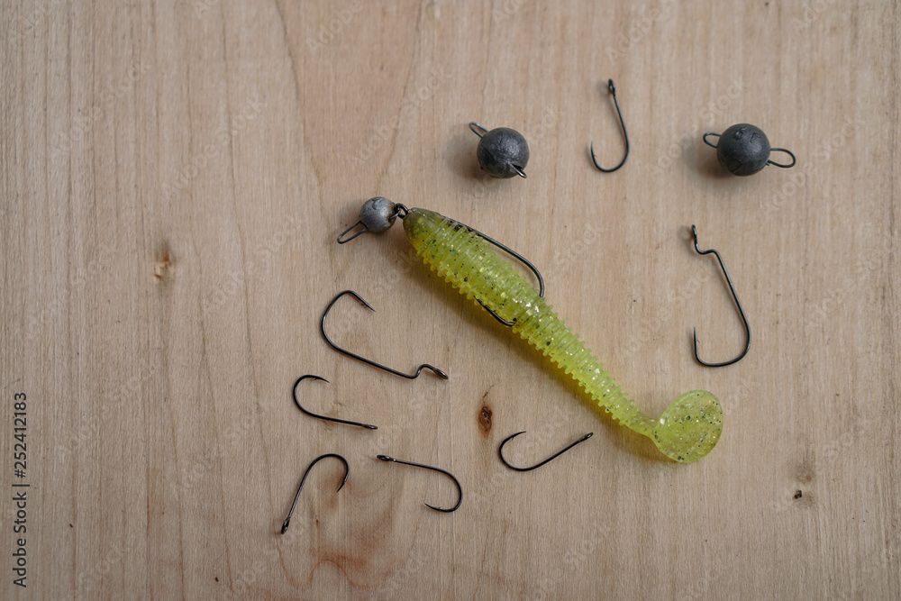 Colorful silicone fishing baits with plummets on wooden table. Various fish and worms and crayfish. Toned image and top view. Stock background, photo Colorful silicone fishing baits with plummets on wooden table. Various fish and worms and crayfish. Toned image and top view. Stock background, photo