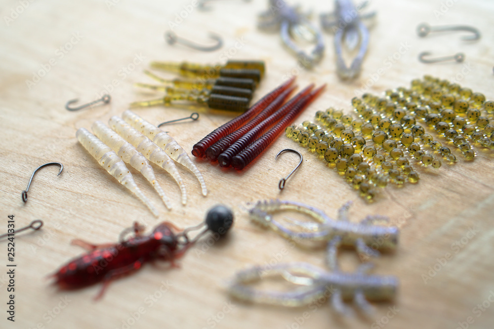 Colorful silicone fishing baits with plummets on wooden table. Various fish and worms and crayfish. Toned image and top view. Stock background, photo Colorful silicone fishing baits with plummets on wooden table. Various fish and worms and crayfish. Toned image and top view. Stock background, photo