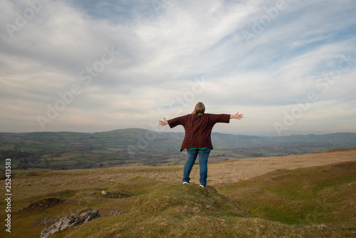 Mature woman with outstretched arms overlooking rural view