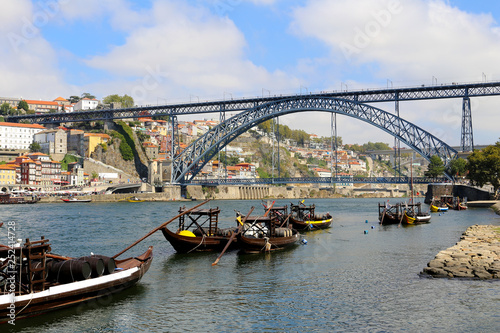 Traditional rabelo boats on the Douro river and view of Dom Luis I Bridge in Porto, Portugal