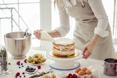 Canvas Print awesome confectioner squeezing cream on cake at kitchen