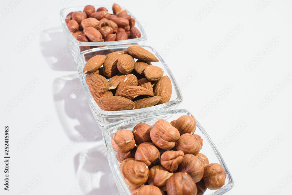 Peanuts, hazelnuts and almonds on a white background Peanuts, hazelnuts and almonds on a white background