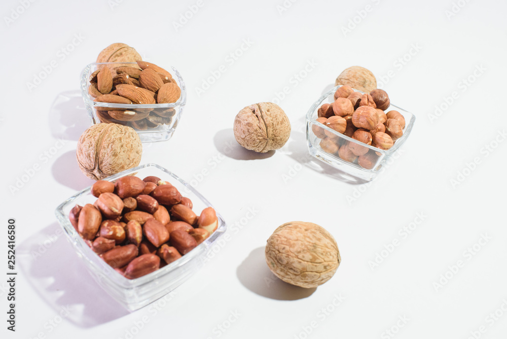 Peanuts, hazelnuts, almonds and walnuts on a white background Peanuts, hazelnuts, almonds and walnuts on a white background