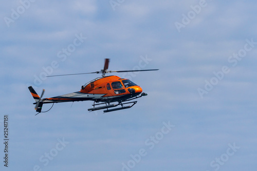 Fliegender Helikopter vor blauem Himmel mit Wolken