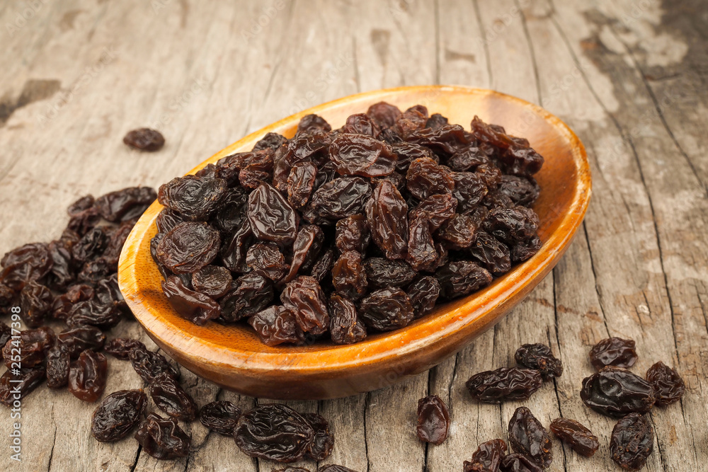 Organic dried Raisins in wood bowls on old wooden table, Currant Organic dried Raisins in wood bowls on old wooden table, Currant