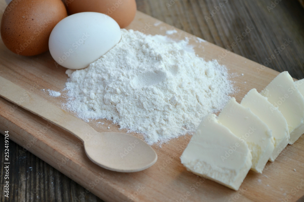 White flour with eggs on a cooking board White flour with eggs on a cooking board