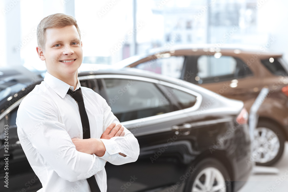 Fototapeta premium Handsome young male car salesman at car dealership