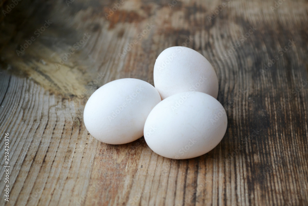 Three white eggs on wooden table Three white eggs on wooden table