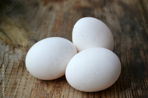 Three white eggs on wooden table