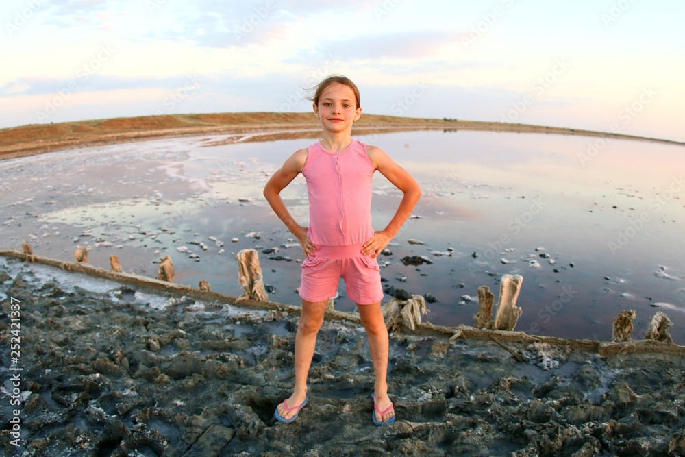 Summer portrait of a girl close-up, on a salt lake in the sunset, girl with contented and playful faces, posing for a photo