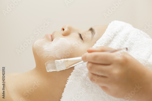 Attractive young Asian woman getting facial treatment at the spa salon photo