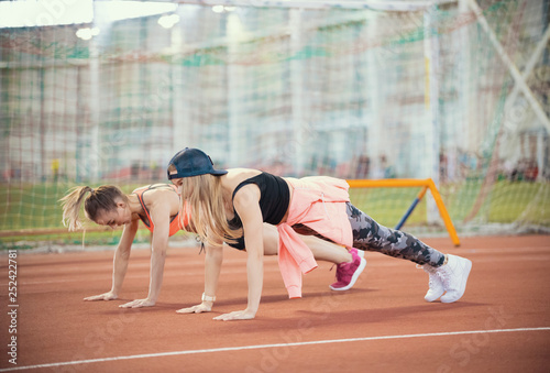 Two young women with doing exercises and warming up before running
