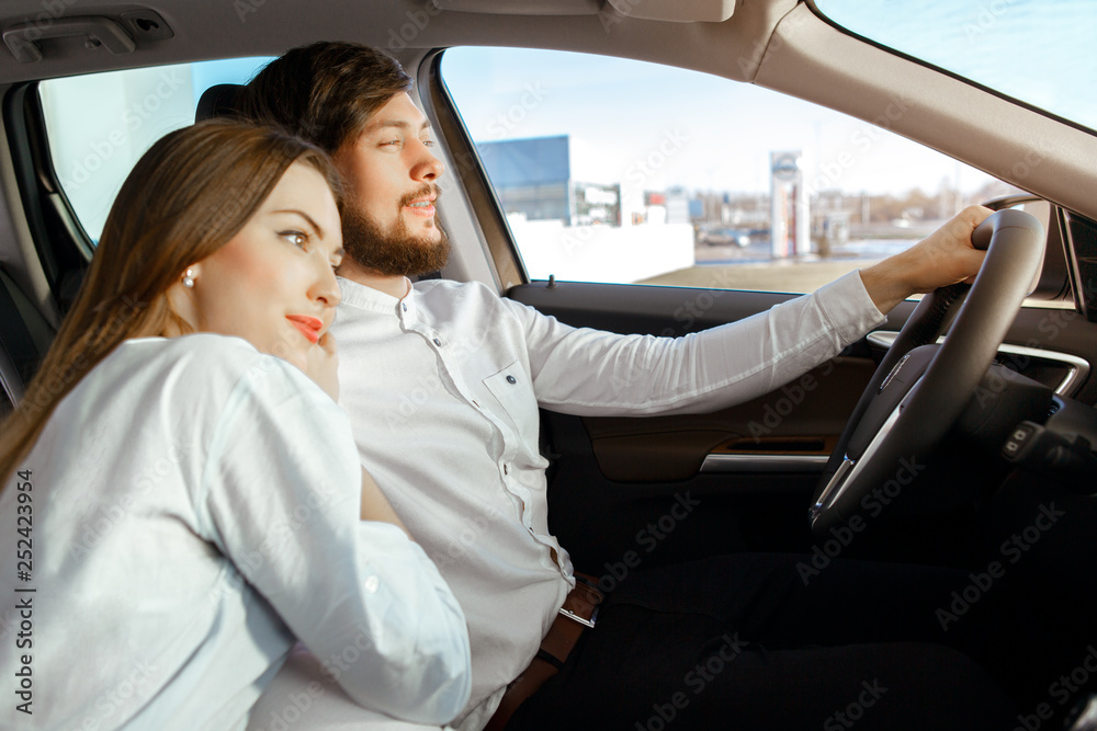 Beautiful happy couple buying a new car at the car dealership center Beautiful happy couple buying a new car at the car dealership center
