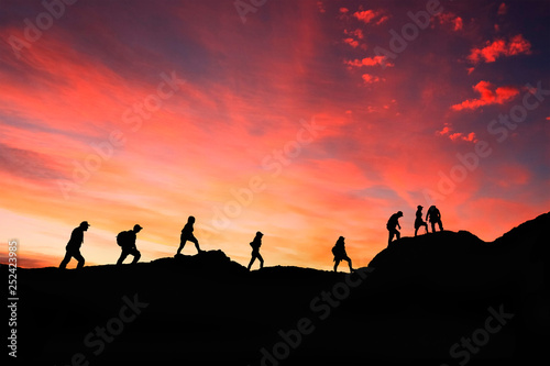 eight friends walk on mountain path in sunset