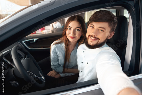 Beautiful happy couple buying a new car at the car dealership center