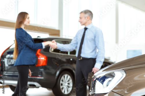 Beautiful young woman buying a car at the dealership center