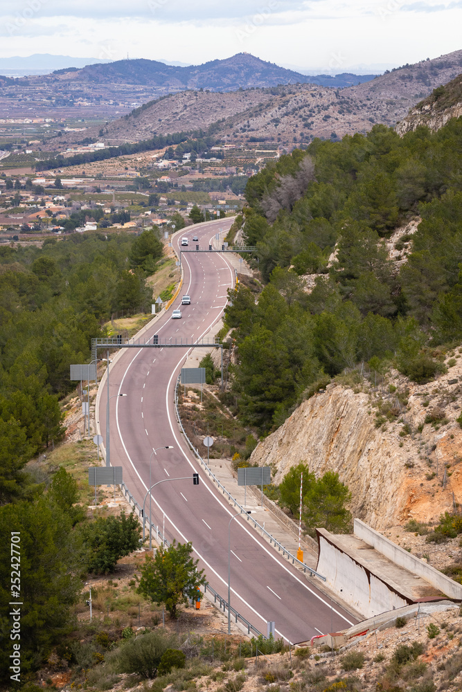 Highway in Spain surrounded by mountains in rural area.