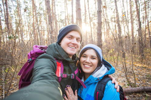 adventure  travel  tourism  hike and people concept - tourists smiling couple taking selfie over trees background