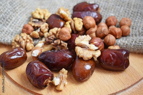 Delicious and healthy nuts and dates on burlap,on a wooden background.