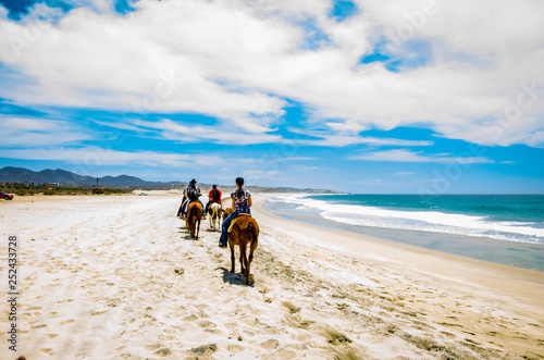 Tourists horseback riding on the beach in Cabo San Lucas, Baja California. photo