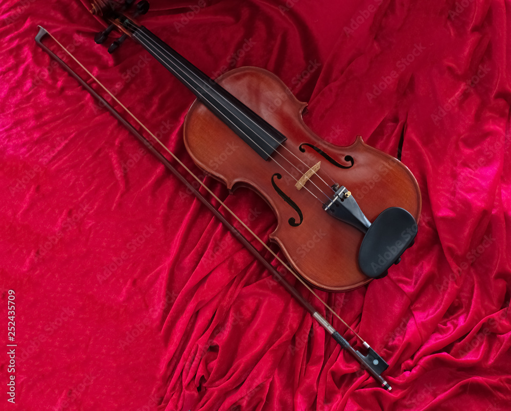 Fototapeta premium The classic violin annd bow put on red cloth background,show detail of instrument