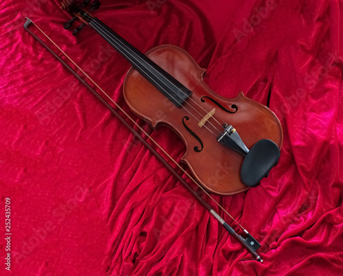 The classic violin annd bow put on red cloth background show detail of instrument