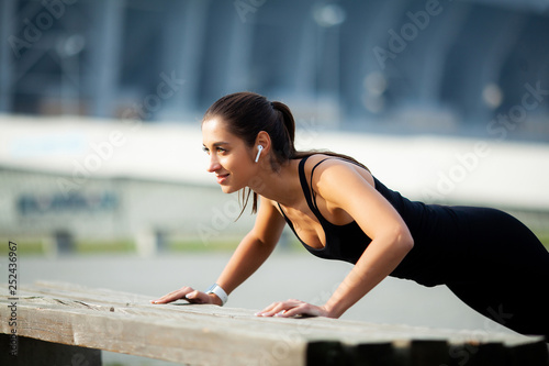 Fitness. Concept of sport, recreation and motivation. Athletic woman standing in plank position outdoors at sunset