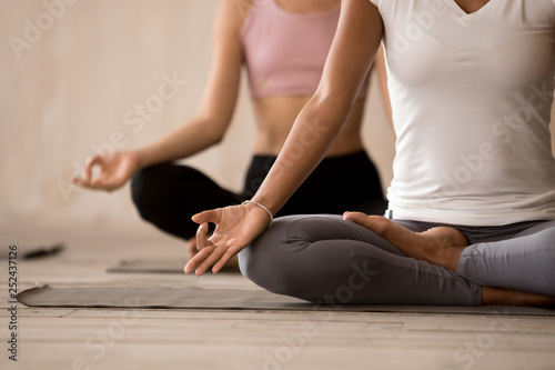 Group of young women practicing yoga, Half Lotus pose