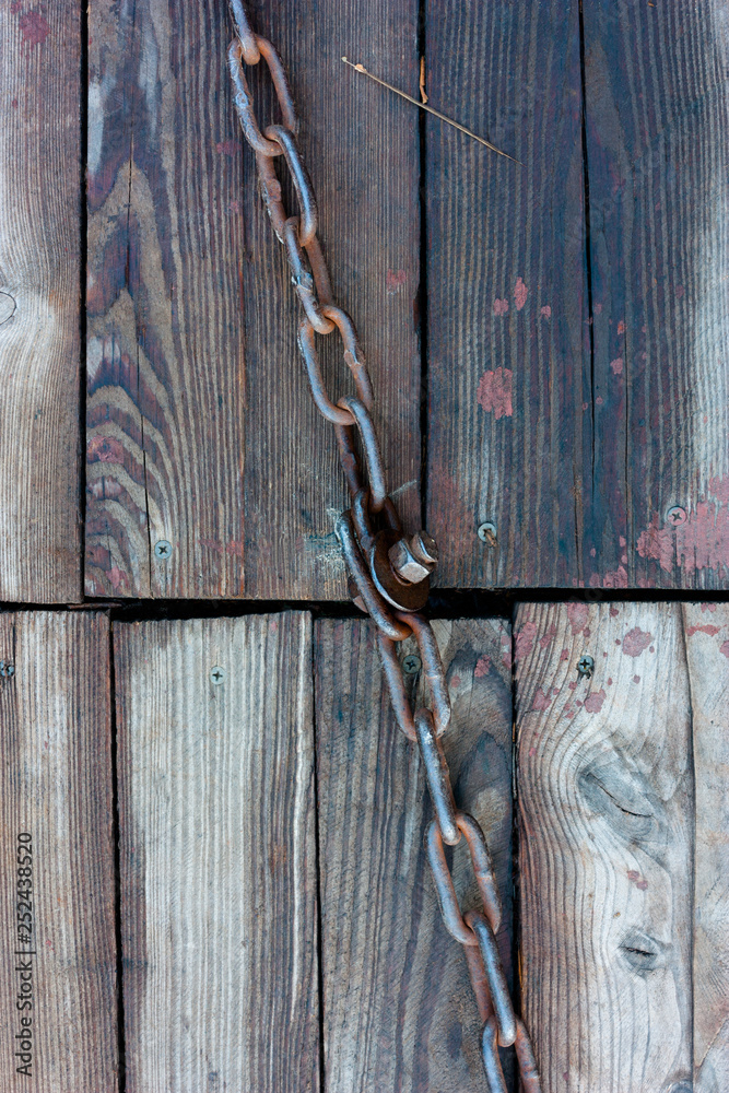 The metal chain lies on the old wet boards. The metal chain lies on the old wet boards.