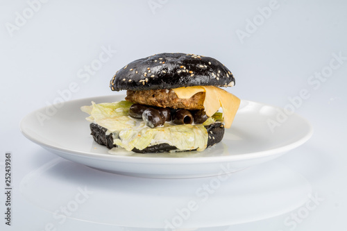 cheeseburger with black bread, beef cutlet, bacon, tomatoes and cheese slices, seasoned with sauce and green salad for a restaurant menu on a white isolated background