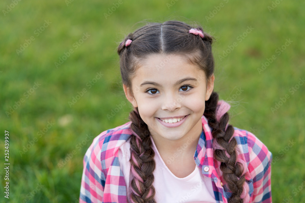 Charming smile. Girl small kid with fashionable braids hairstyle. Fashion trend. Salon and hair care. Girl smile face outdoors. Pleasant walk in park. Smile and joy. Fashionable hairstyle for kids Charming smile. Girl small kid with fashionable braids hairstyle. Fashion trend. Salon and hair care. Girl smile face outdoors. Pleasant walk in park. Smile and joy. Fashionable hairstyle for kids