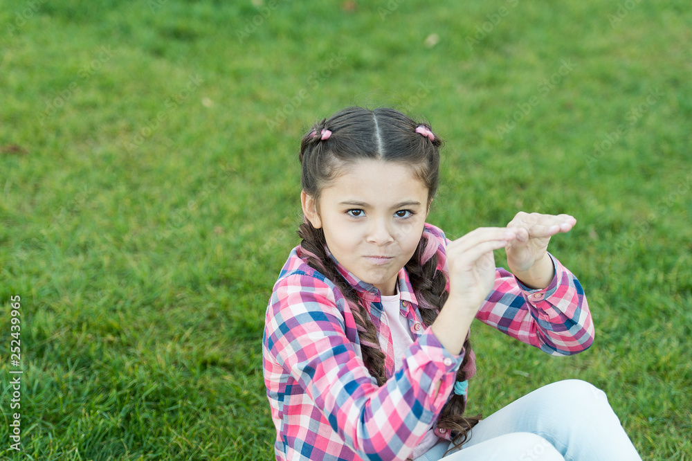 Kid gadabout. Girl little kid spend leisure outdoors in park. Girl sit on grass in park. Child enjoy spring sunny weather while sitting at meadow in park. Springtime concept. Park and garden Kid gadabout. Girl little kid spend leisure outdoors in park. Girl sit on grass in park. Child enjoy spring sunny weather while sitting at meadow in park. Springtime concept. Park and garden