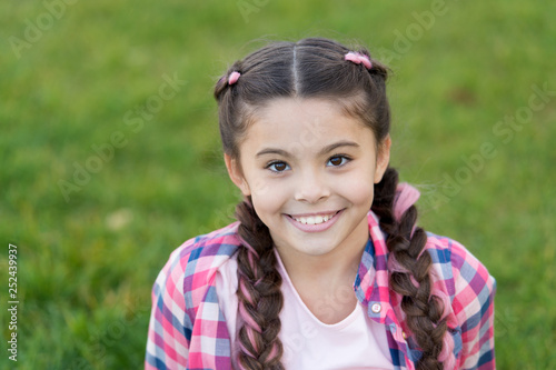Charming smile. Girl small kid with fashionable braids hairstyle. Fashion trend. Salon and hair care. Girl smile face outdoors. Pleasant walk in park. Smile and joy. Fashionable hairstyle for kids