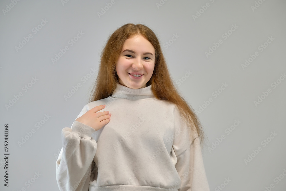 Concept portrait of a cute pretty teenager girl with red hair against gray background smiling and talking. Concept portrait of a cute pretty teenager girl with red hair against gray background smiling and talking.