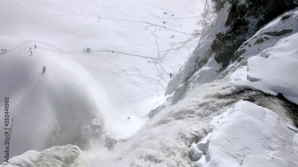 Slow motion view looking down over snowy frozen Montmorency Falls waterfall in Quebec, Canada in the winter.