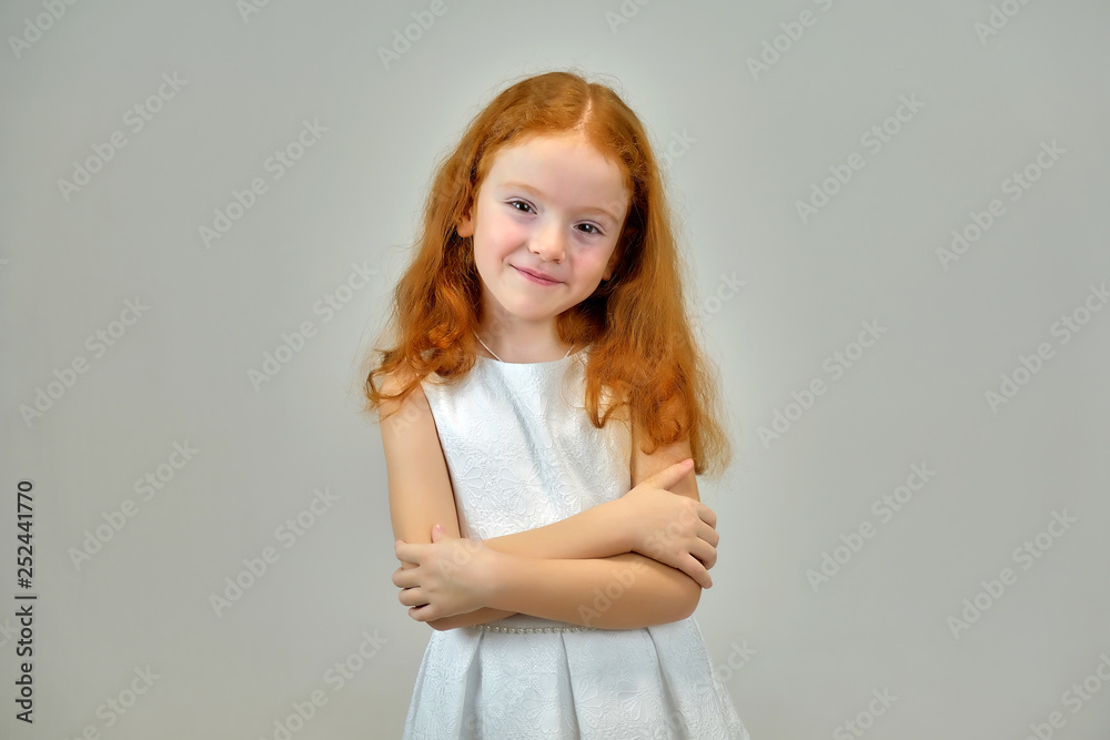Concept portrait of a cute pretty child girl with red hair on a gray background smiling and talking Concept portrait of a cute pretty child girl with red hair on a gray background smiling and talking