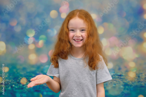 Concept portrait of a cute pretty child girl with red hair on a color background smiling and talking. © Вячеслав Чичаев