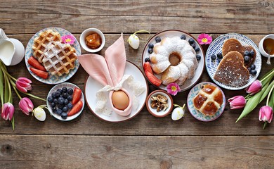Easter festive dessert table with hot cross buns, cakes, waffles and pancakes. Overhead view
