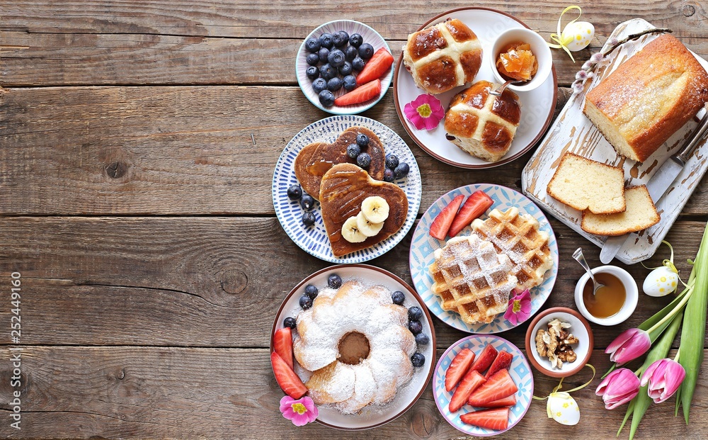 Easter festive dessert table with hot cross buns, cakes, waffles and pancakes. Overhead view Easter festive dessert table with hot cross buns, cakes, waffles and pancakes. Overhead view