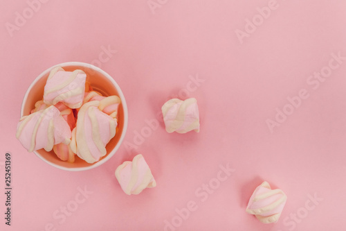 Marshmallow in a white glass on a pink background. Minimal style. Top view, copy-space.