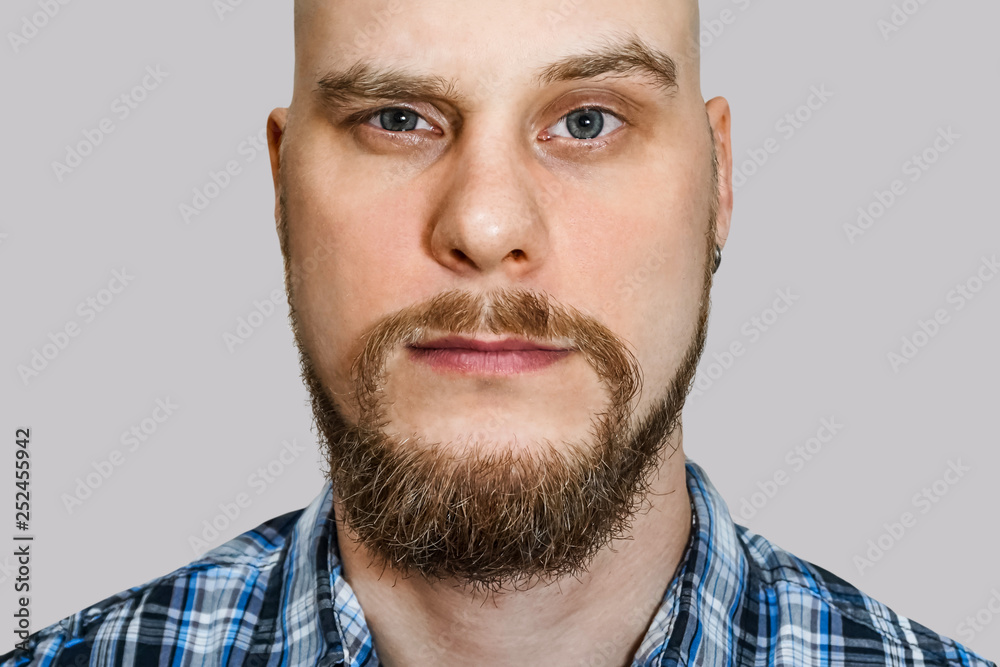 portrait of a serious, pensive, bald guy with a beard with narrowed eyes looking at the camera on an isolated background portrait of a serious, pensive, bald guy with a beard with narrowed eyes looking at the camera on an isolated background