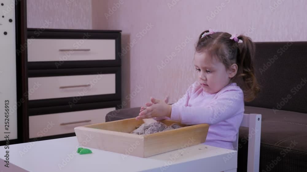 Cute baby girl playing with kinetic sand at the table Cute baby girl playing with kinetic sand at the table
