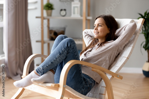 Smiling young woman relaxing leaning back in comfortable chair at home