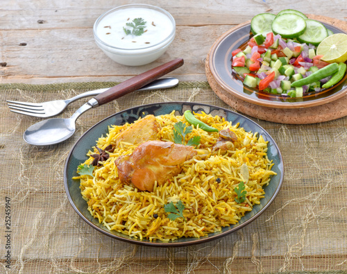 Chicken Biryani, a deleciously colorful rice dish filled with spicy marinated chicken  along with salad & raita.