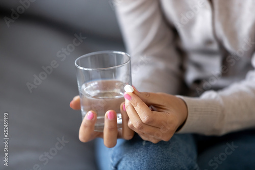 Papier peint Close up sick woman holding glass with water and pill in hands