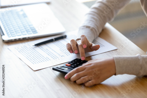 Close up young woman using calculator, calculating finance at workplace