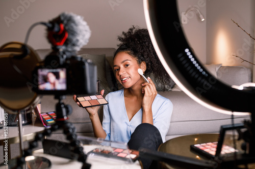 Female vlogger recording a makeup tutorial, applying cosmetics with brush photo