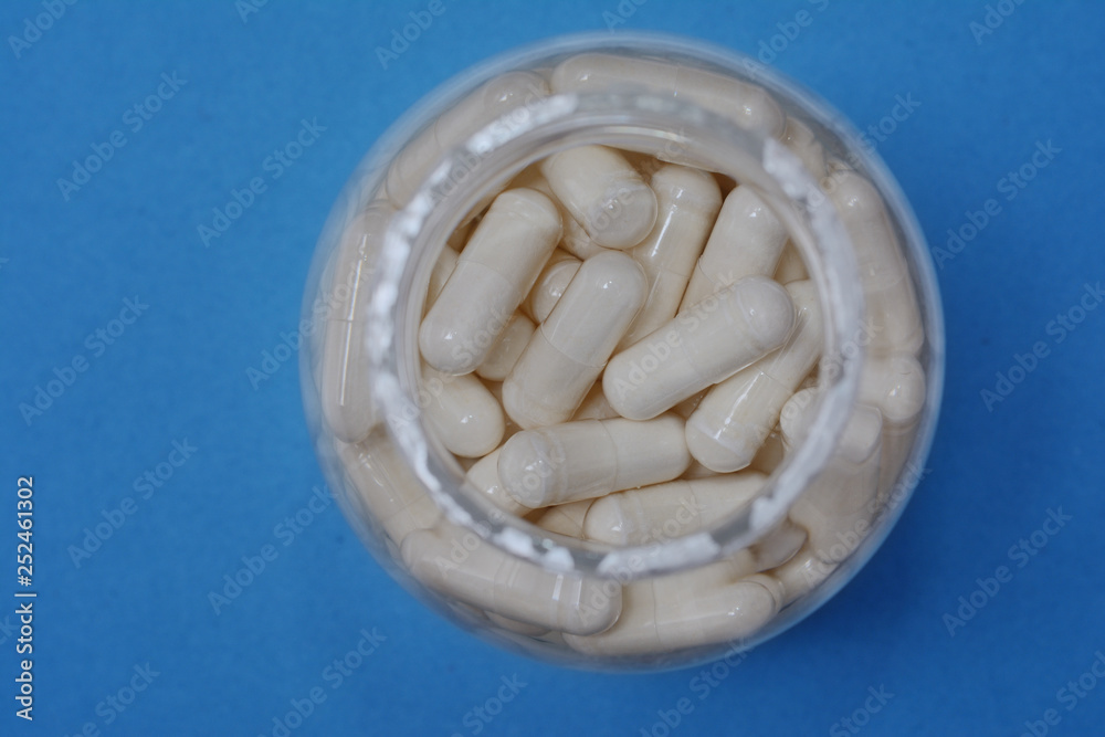 jar with medical capsules close up on a blue background, the top view jar with medical capsules close up on a blue background, the top view