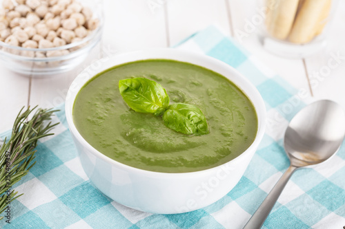Green cream soup of spinach and chickpeas on concrete wood background